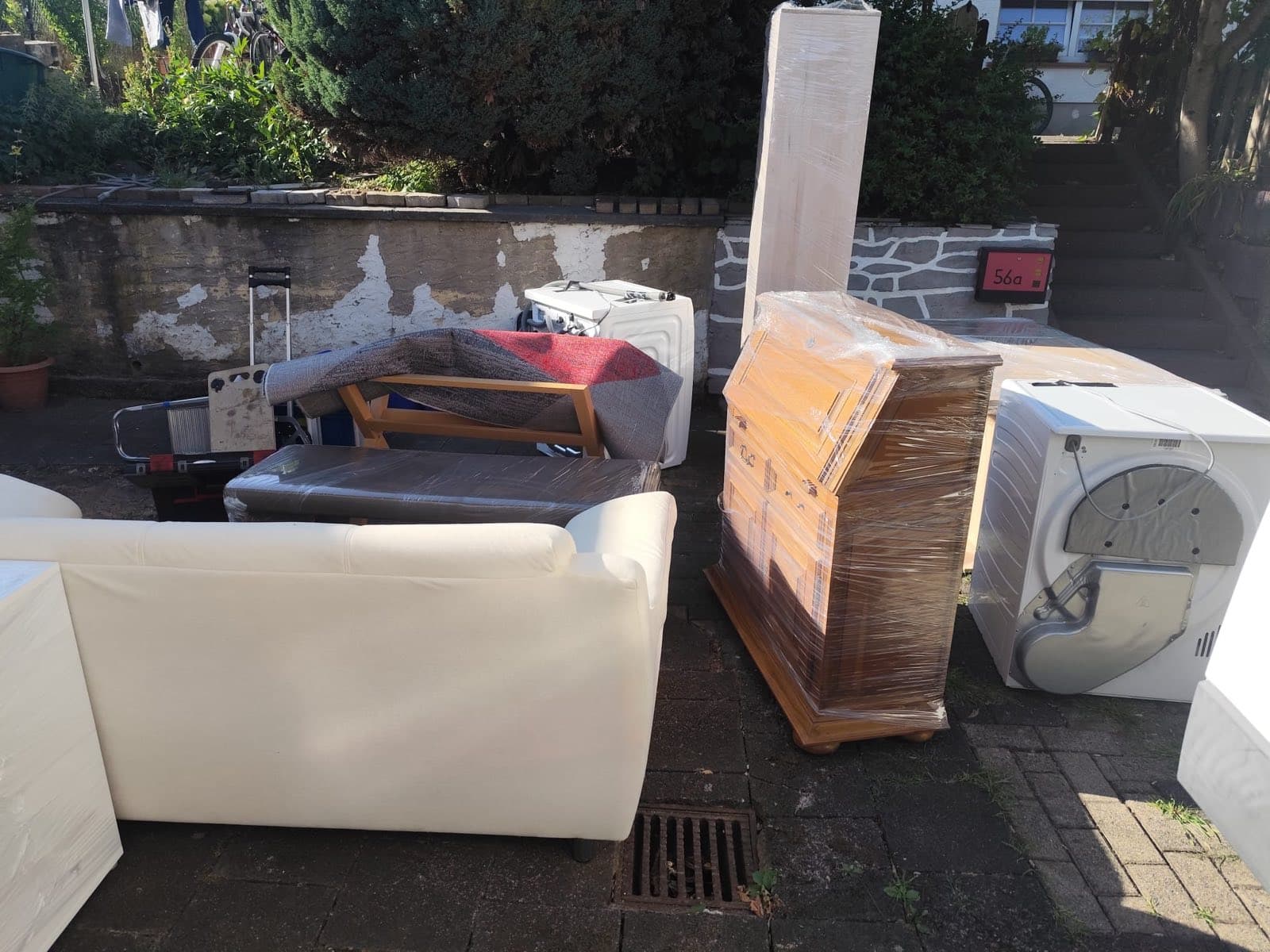 Sofa, Kommode, Waschmaschine und Trockner stehen zum Abtransport vor dem Haus