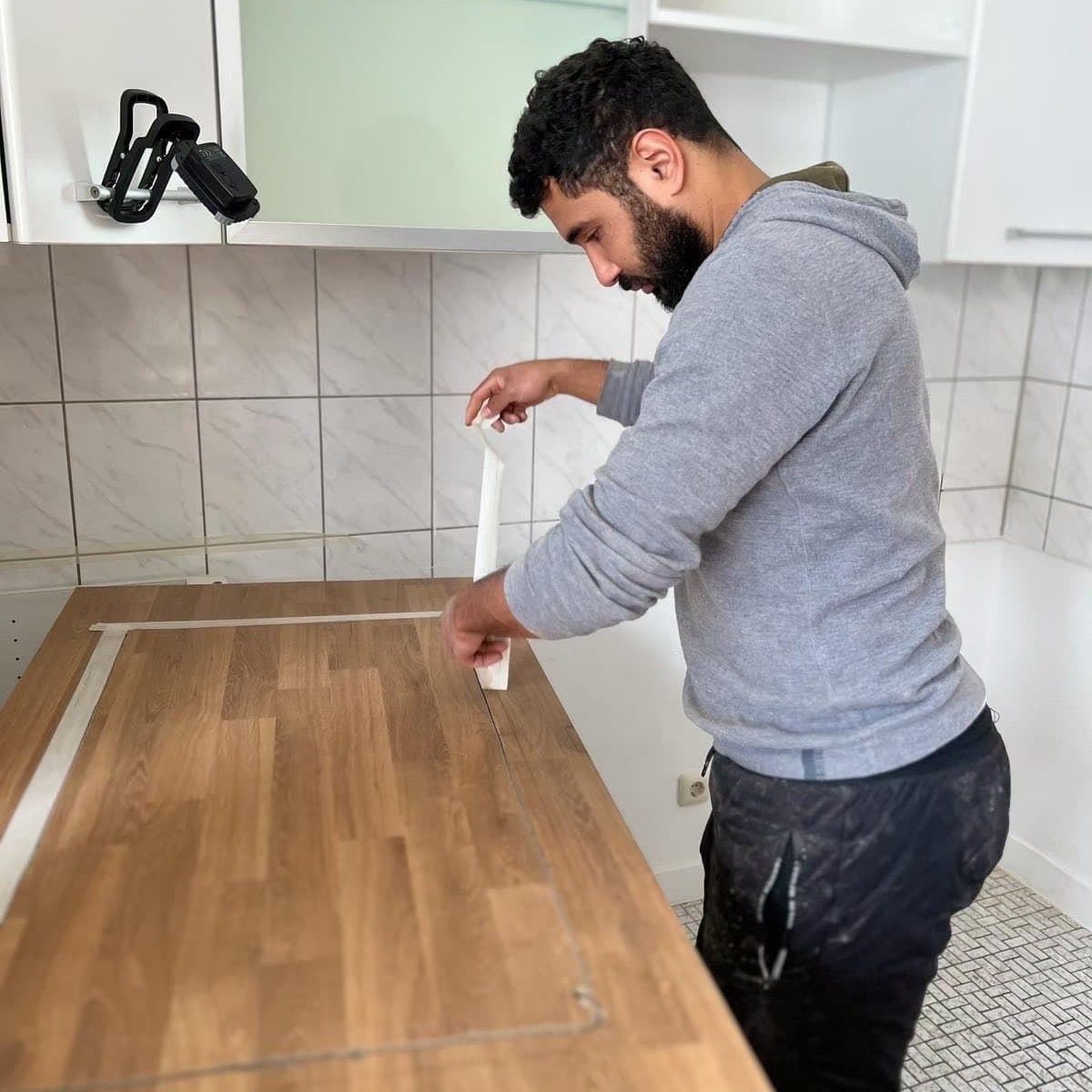 Ein Mitarbeiter zieht Dichtband an der Kante einer neuen Küchenarbeitsplatte ab