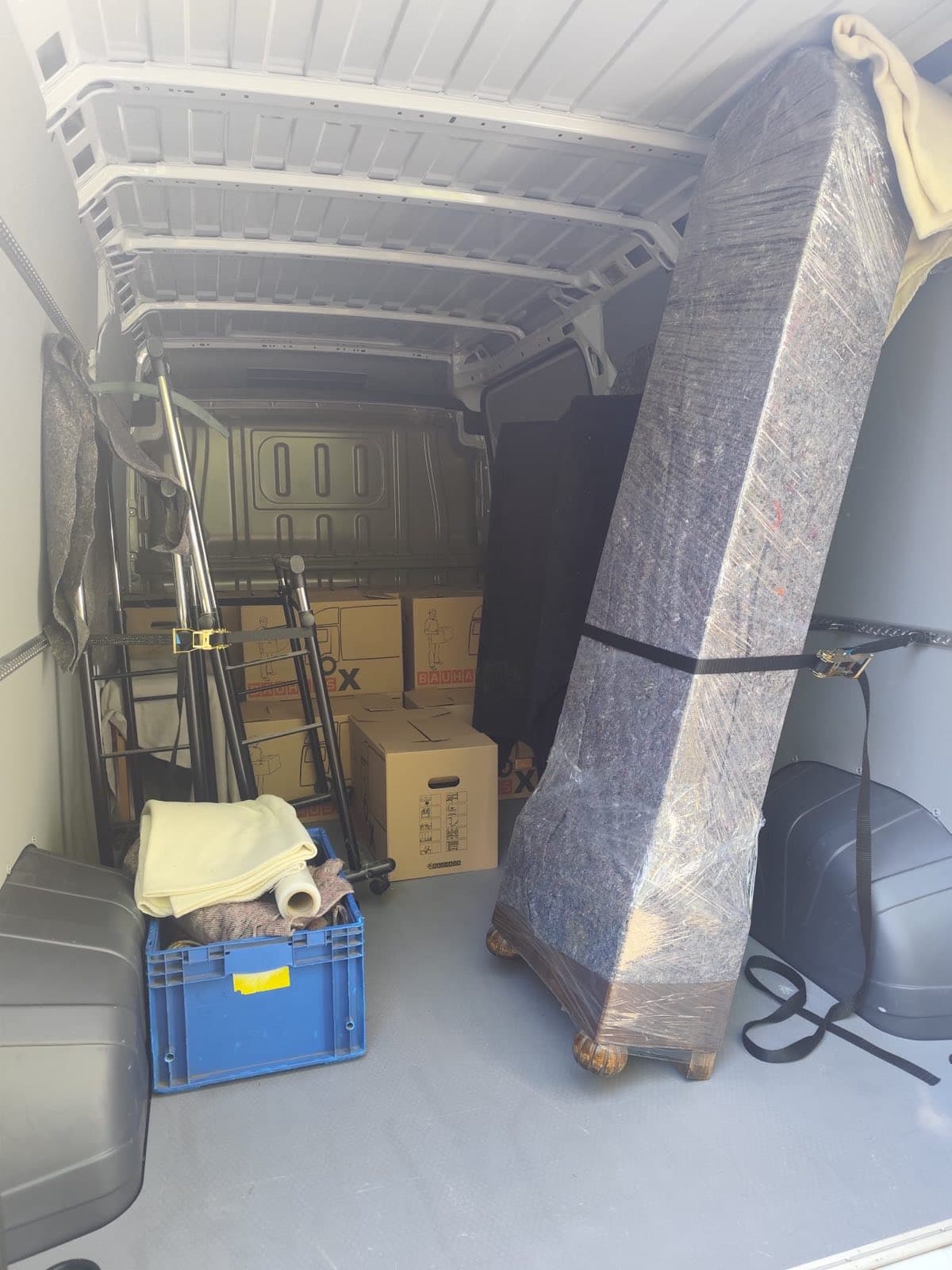 Laderaum mit Umzugsdecken, Spanngurten und einem senkrecht verzurrten Sofa